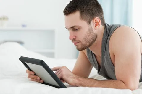 Handsome man using a tablet computer while lying on his belly Stockfoto's