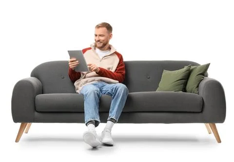 Handsome man using tablet computer on sofa against white background Stock Photos