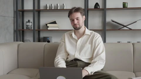 Handsome Man On Video Call Gesturing While Talking, Sitting Comfortably On Sofa 스톡 동영상 303759834