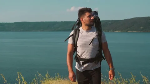 The handsome man walking with backpack along the coast. slow motion Stock Footage 159732997