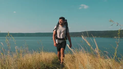 The handsome man walking with backpack along the coast. slow motion Stock Footage 159733328