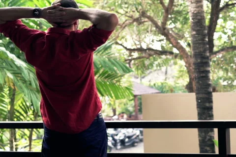Handsome man walking out and stretching arms on terrace NTSC Vídeo Stock 51609100