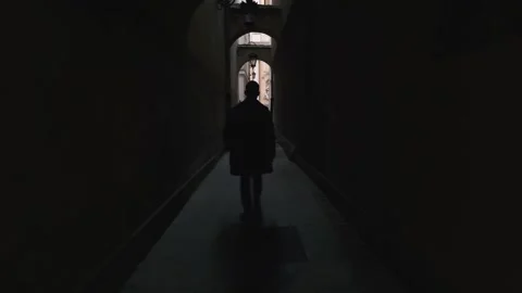 Handsome man walks in a tunnel between houses in the old town Stock Footage 132311938