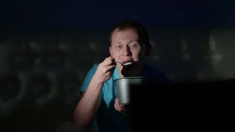 A handsome man watching an interesting program on TV, eating ice cream Stock Footage 130250595