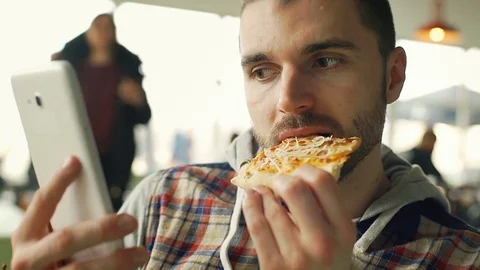 Handsome man watching something an tablet and smiling to the camera while eating Stock Footage 73954251