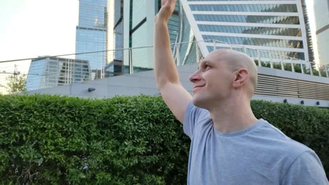 Handsome man waves to someone while walking around the big city Stock Footage 201635928