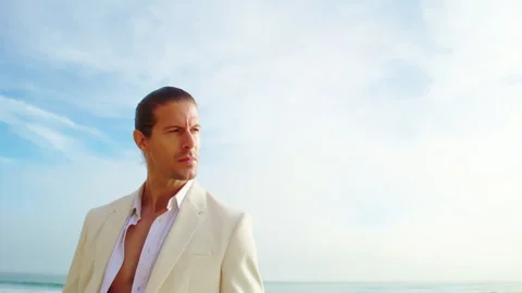 Handsome man in white suit posing near Pacific ocean. Male portrait Stock Footage 245949989