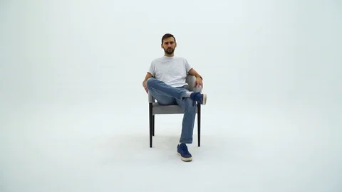 Handsome man in white tshirt and chair on a white background. Man gets up from Stock Footage 113002853