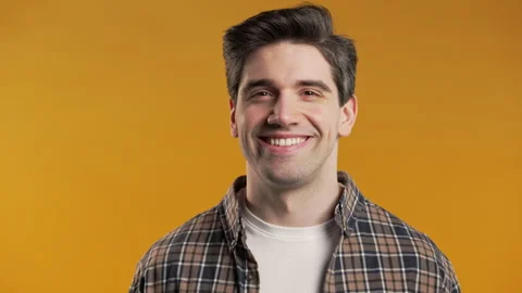 Handsome man winking eye, flirting, smiling to camera. Guy in studio on yellow Stock Footage 274720785