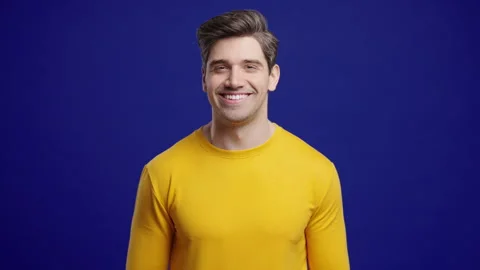 Handsome Man Winking Eye, Flirting, Smiling To Camera. Guy In Studio On Blue Stock Footage 321097003
