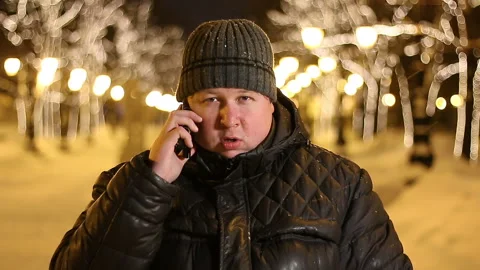 Handsome man in the winter talking on his phone on a city street on a frosty Stock Footage 104820279