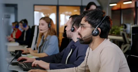 Handsome man working in call center and talking with client. Male worker in Stock Footage 179951584