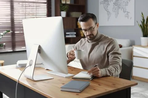 Handsome man working with computer at desk indoors. Home office Stock Photos