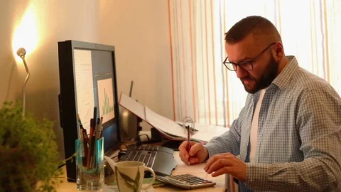 Handsome man working from home calculating financial data Stock Footage 71657985