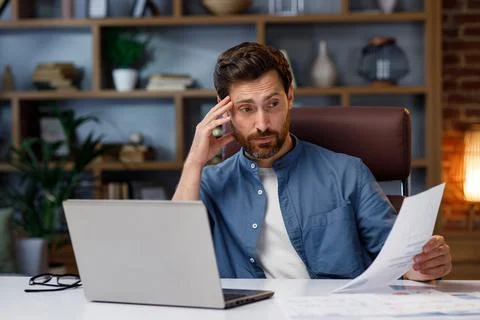 Handsome man working on laptop while sitting at home office. In stress, he looks 스톡 사진
