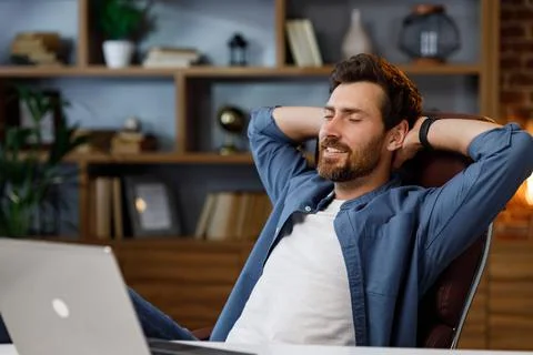 Handsome man working on laptop while sitting at home office. Relax after work Stock Photos