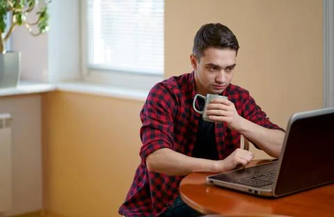Handsome man working using computer laptop and drinking a cup of coffee at .. Stock Photos