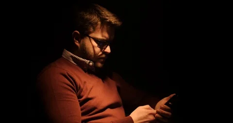 A handsome man writes an SMS in a dark room Stock Footage 88059018