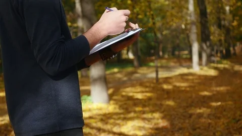 Handsome man writes something by pen on a piece of paper Stock Footage 83611623