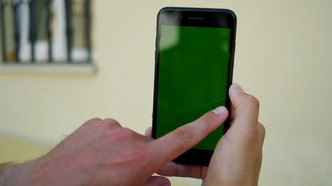 Handsome man's hand using phone with green mock-up screen and doing swiping Stock Footage 112348306