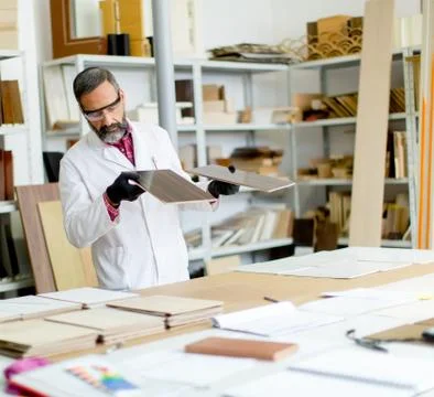 Handsome mature engineer testing colors on wooden specimens Foto stock