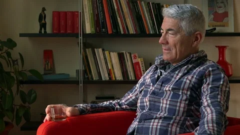 Handsome mature man drinking whisky at home after a day of work Video stock 73127093