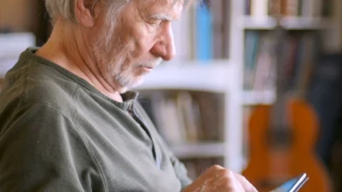 A handsome mature senior man using digital tablet online in his home Stock Footage 78448401