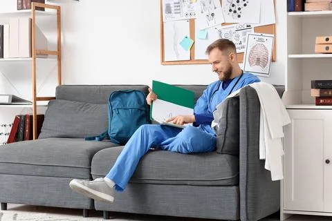 Handsome medical intern studying with folder on sofa in clinic Stock Photos
