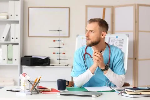 Handsome medical intern studying at table in clinic Stock Photos