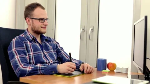 Handsome men in glasess, sitting behind the desk and using computer.. Stock Footage 49057786