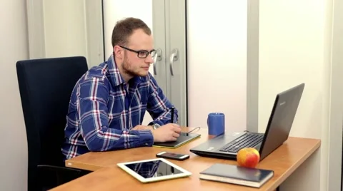 Handsome men sitting behind the desk and using computer.. Stock Footage 49057864