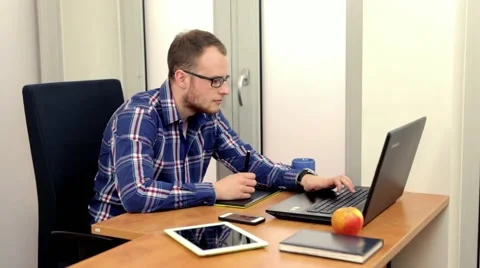 Handsome men sitting behind the desk and using computer.. Stock-Footage 49057900