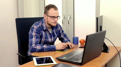 Handsome men sitting behind the desk and using  two computers at the same time Stock Footage 49057935
