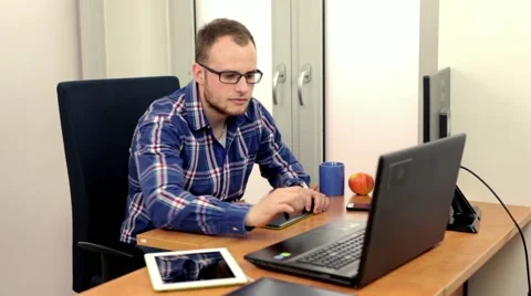Handsome men sitting behind the desk and using  two computers at the same time Stock-Footage 49058008