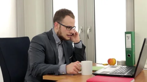 Handsome men sitting behind the desk and talkin by the phone Stock Footage 49338840