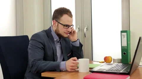 Handsome men sitting behind the desk and talking by the phone, Stock Footage 49339105
