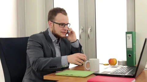 Handsome men sitting behind the desk and talking by the phone Video stock 49339254