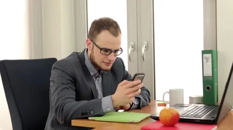 Handsome men sitting behind the desk and making video conversation by the phone. Stock Footage 49339565