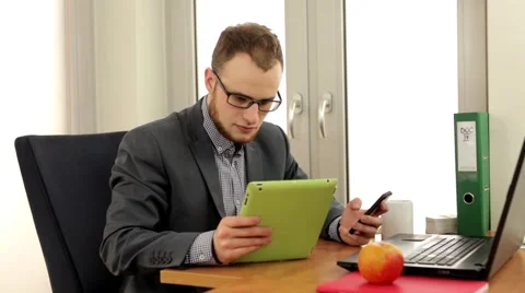 Handsome men sitting behind the desk with tablet pc and laptop Stock Footage 49339855