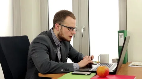Handsome men sitting behind the desk and doing work on his computer Stock Footage 49340267