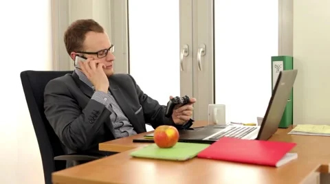 Handsome men sitting behind the desk and talking by the phone Stock Footage 49340802