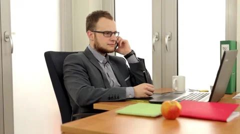 Handsome men sitting behind the desk and talking thru the phone. Stock Footage 49340950