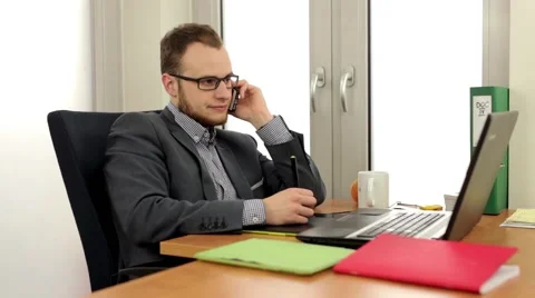 Handsome men sitting behind the desk, talking thru the phone Stock Footage 49341825
