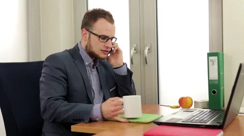 Handsome men sitting behind his desk and talking by the phone Stock Footage 49339177