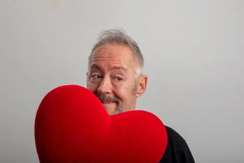 Handsome middle-aged gray-haired and bearded man holding a red heart Stock Photos