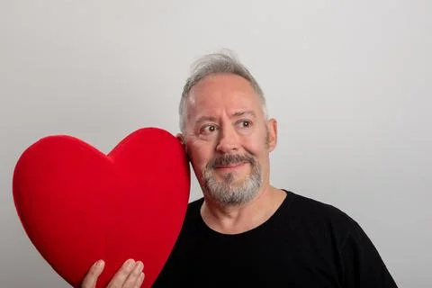 Handsome middle-aged gray-haired and bearded man holding a red heart Stock Photos