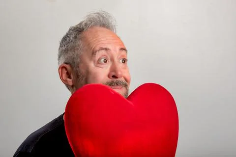 Handsome middle-aged gray-haired and bearded man holding a red heart Stock Photos