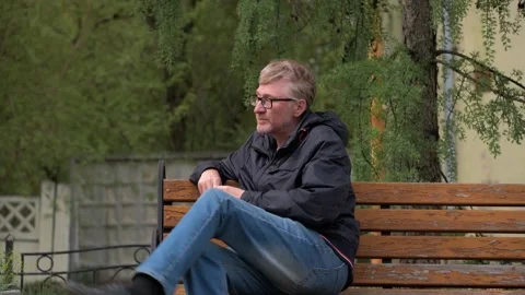 Handsome middle aged man in blue jacket and jeans gets up from bench and leaves. Stock Footage 252108060