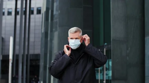 Handsome middle aged man putting on face mask in the city and looking at camera. Stock Footage 165209945
