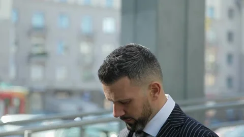 Handsome middle-aged man stands on the background of the city with his head down Stock Footage 93831369